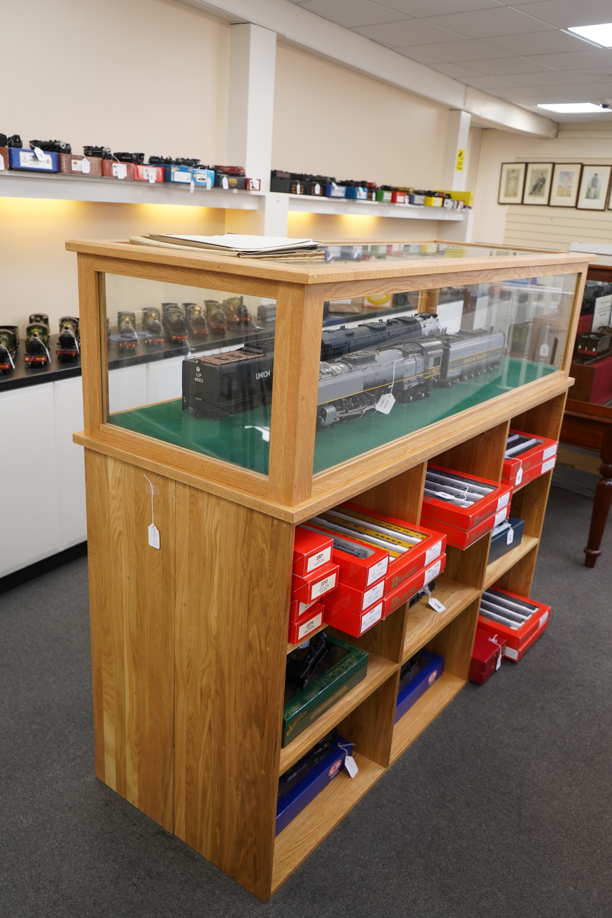 An engineered oak display stand, with a removable glazed top, and double sided base divided into nine compartments on each side, dimensions; 160cm wide, 60cm deep, 141cm high (contents for display purposes only and not i